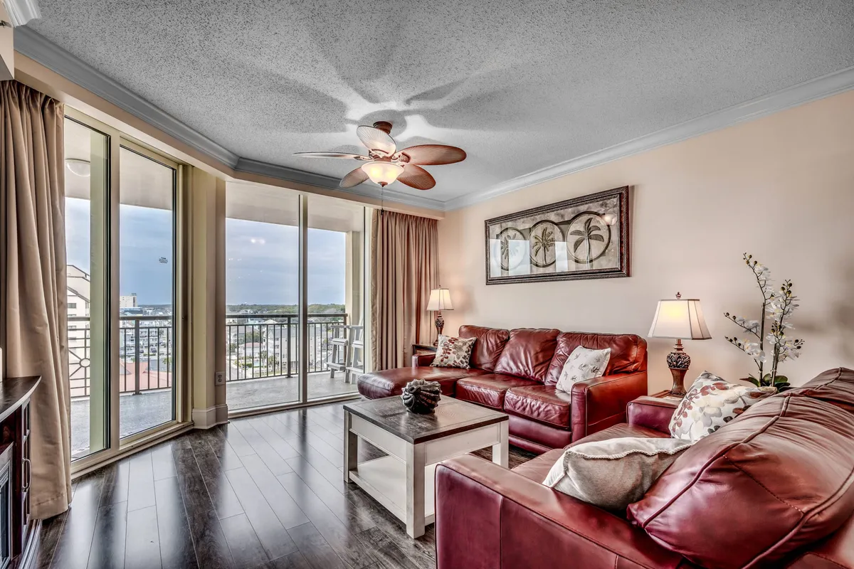 This interior scene features red leather sofas, glass balcony doors, decorative wall art, and table lamps. The space offers views outside and a cozy setting for social interactions or quiet relaxation, perfectly blending indoor comfort with hints of the resort's scenic surroundings.