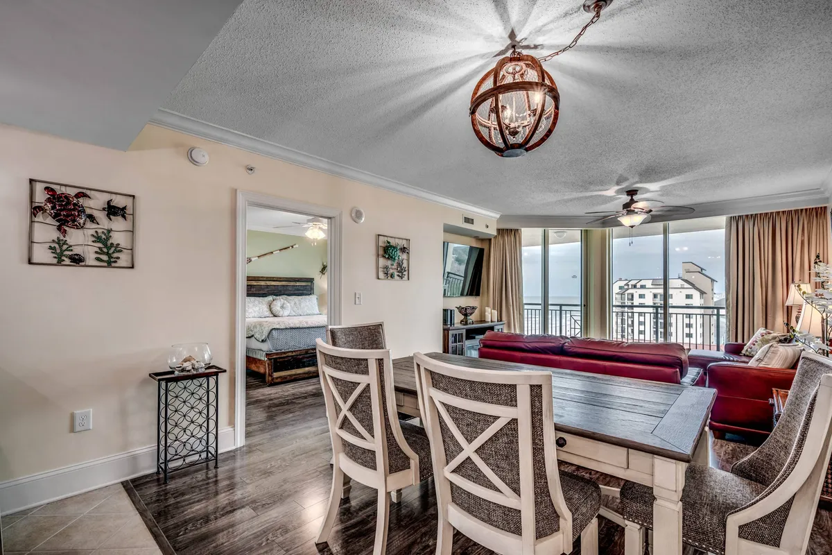 A spacious, open-concept living and dining area with a comfortable seating arrangement, a large dining table, and expansive windows offering stunning ocean views. The scene is filled with natural light, creating a warm and inviting atmosphere ideal for gathering and relaxation.