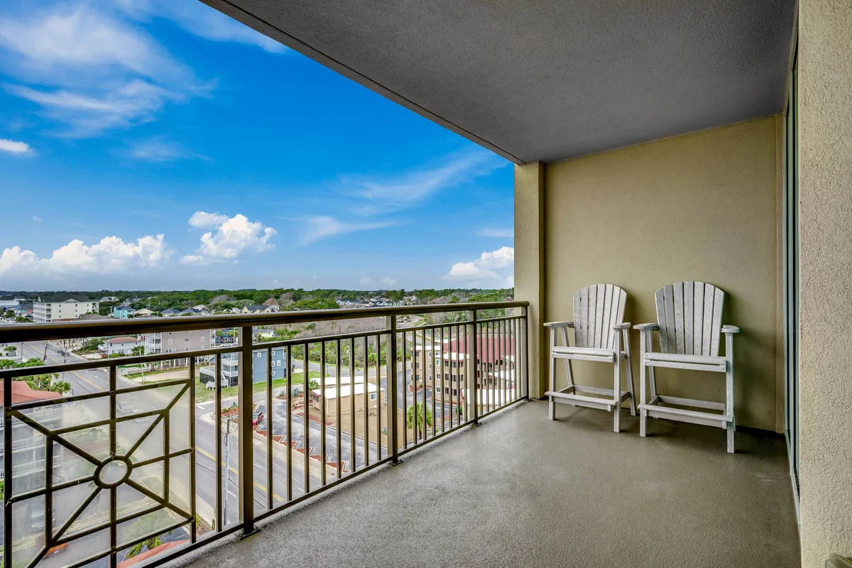 This exterior image features a balcony lined with adirondack chairs, overlooking an expansive sky. The inviting seating suggests morning relaxation or evening gatherings, perfectly aligning with the idea of unwinding after a day of golf, entertainment, or nightlife.