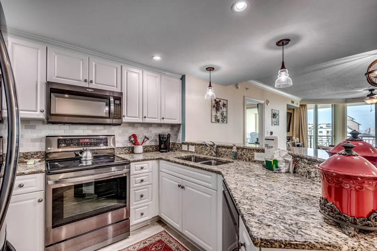 A stylish, fully equipped kitchen with gleaming granite countertops, modern appliances, and pops of color from red cookware, inviting guests to linger over a leisurely breakfast or prepare a romantic meal.