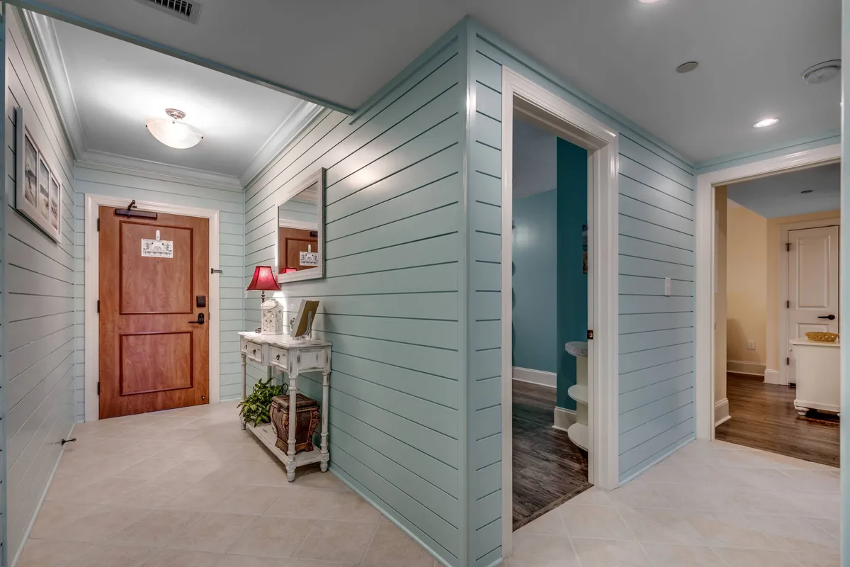 An inviting interior entryway showcases a wooden front door, a stylish white console table, and a decorative lamp and mirror—capturing the ambiance of coming home to a welcoming, comfortable space after a day of adventures.